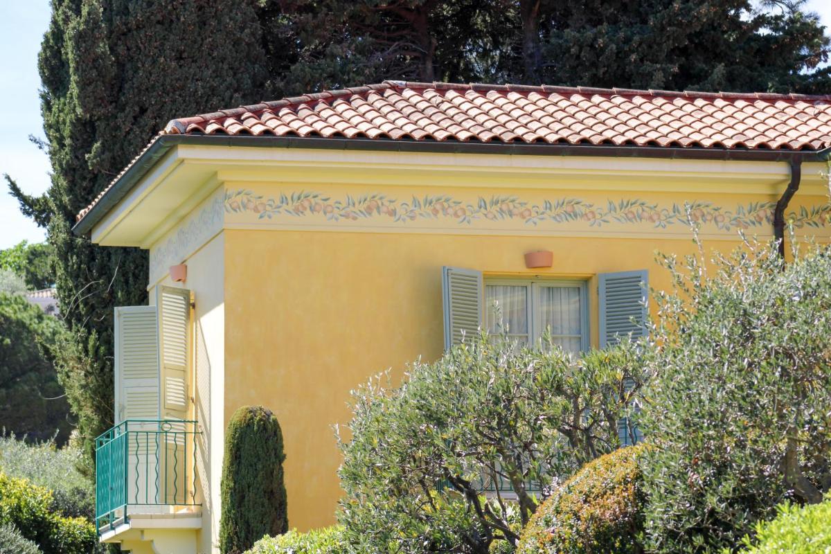une maison jaune avec un balcon et des arbres dans l'établissement Hotel Royal-Riviera, à Saint-Jean-Cap-Ferrat