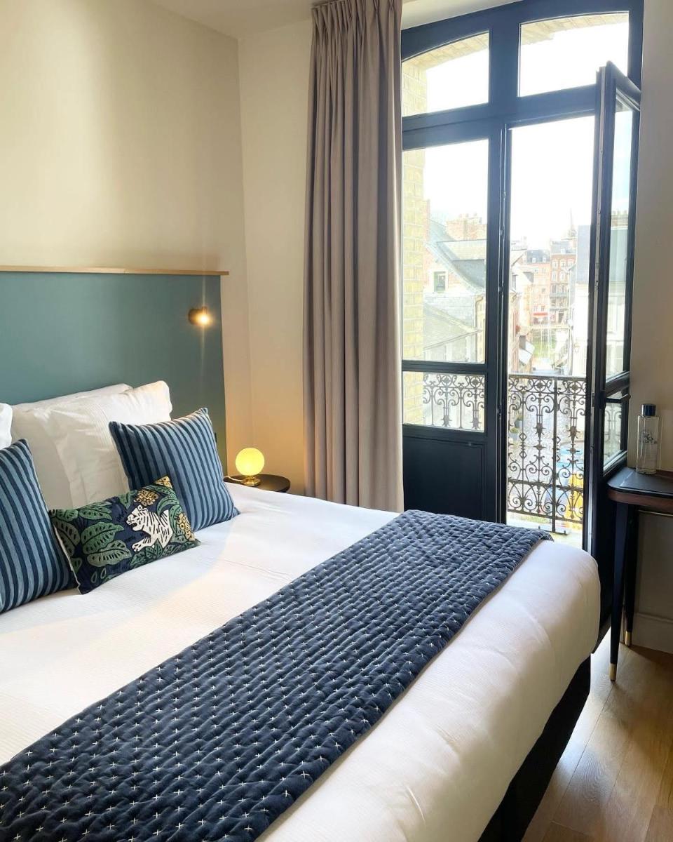 une chambre avec un lit et une grande fenêtre dans l'établissement L'INVITATION AU VOYAGE - Hôtel & Spa, à Honfleur