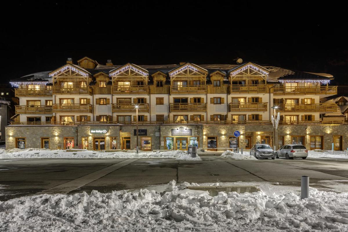 un grand bâtiment dans la neige la nuit dans l'établissement CGH Résidence Boutique Le Napoléon, à Montgenèvre