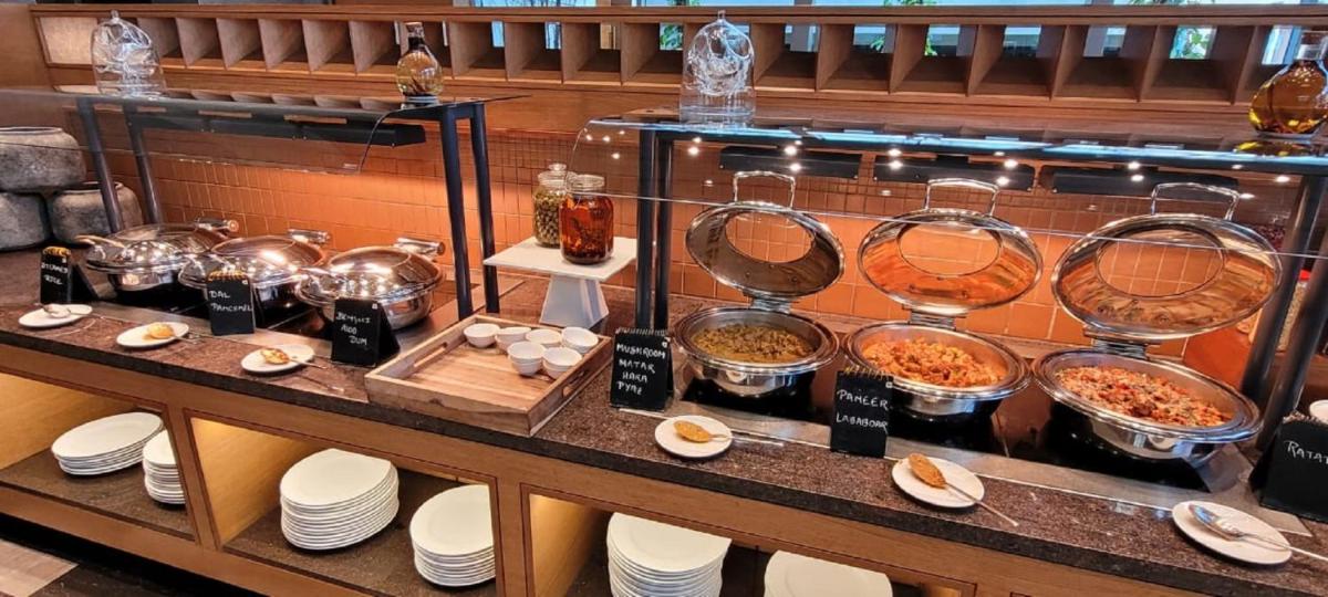 a buffet of food on a table with bowls and plates at Taj City Centre New Town, Kolkata in Kolkata a buffet of food on a table with bowls and plates at Taj City Centre New Town, Kolkata in Kolkata
