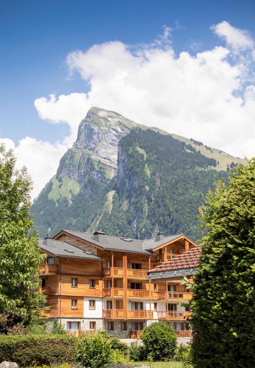 un bâtiment avec une montagne en arrière-plan dans l'établissement Résidence Club MMV Samoens, à Samoëns