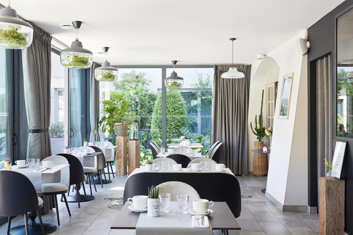 un restaurant avec des tables et des chaises et de grandes fenêtres dans l'établissement Le Général d'Elbée Hotel & Spa - Teritoria, à Noirmoutier-en-l'lle