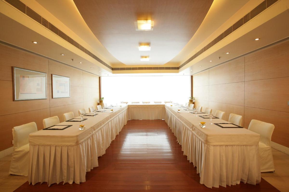 a row of tables in a room with white chairs at Jaypee Siddharth in New Delhi a row of tables in a room with white chairs at Jaypee Siddharth in New Delhi