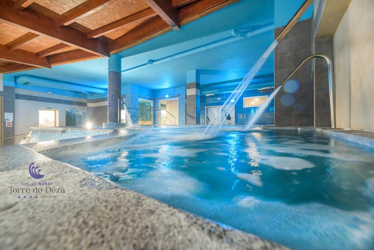 Una gran piscina en un hotel con iluminación azul. en Hotel Spa Norat Torre Do Deza 4* Superior, en Lalín