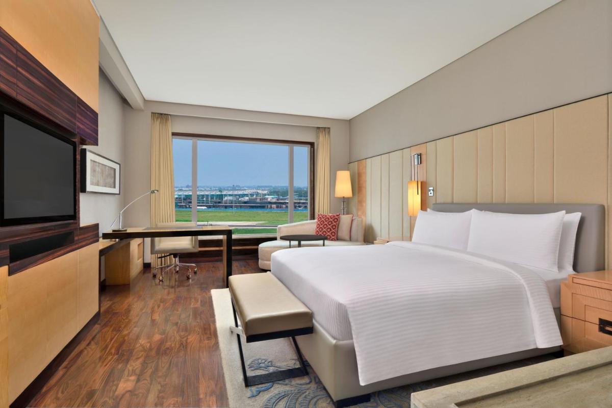 a bedroom with a bed and a desk and a television at JW Marriott Hotel New Delhi Aerocity in New Delhi a bedroom with a bed and a desk and a television at JW Marriott Hotel New Delhi Aerocity in New Delhi