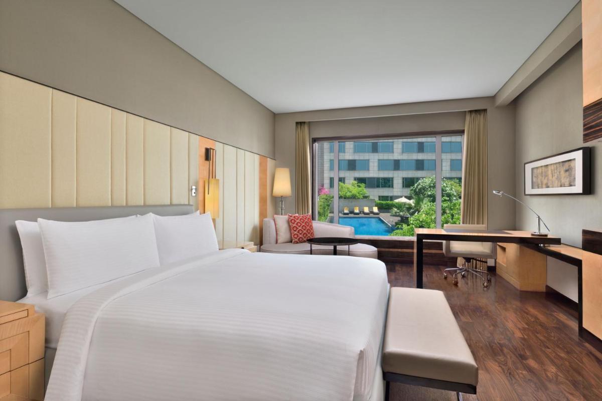 a bedroom with a large white bed and a desk at JW Marriott Hotel New Delhi Aerocity in New Delhi a bedroom with a large white bed and a desk at JW Marriott Hotel New Delhi Aerocity in New Delhi