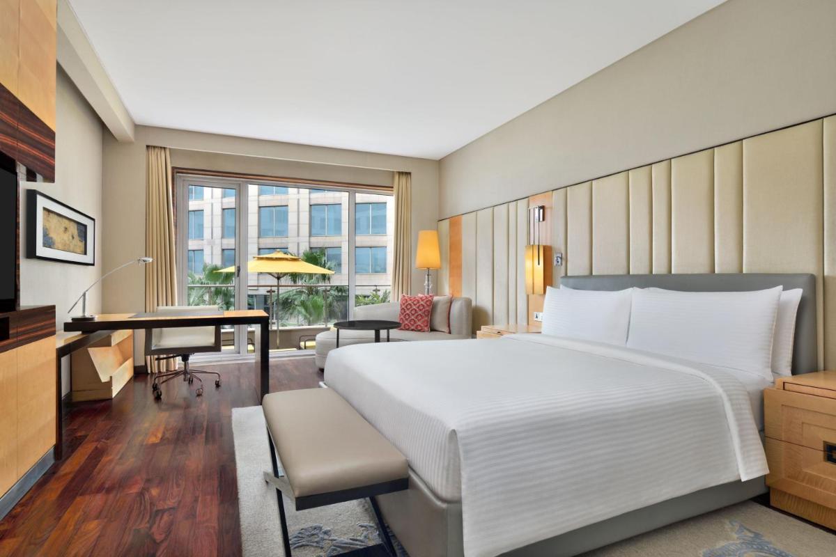 a bedroom with a large white bed and a desk at JW Marriott Hotel New Delhi Aerocity in New Delhi a bedroom with a large white bed and a desk at JW Marriott Hotel New Delhi Aerocity in New Delhi