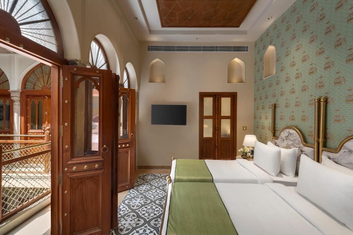 a hotel room with a bed and a balcony at Haveli Dharampura & Golden Haveli- UNESCO awarded Boutique Heritage Hotel in New Delhi a hotel room with a bed and a balcony at Haveli Dharampura & Golden Haveli- UNESCO awarded Boutique Heritage Hotel in New Delhi
