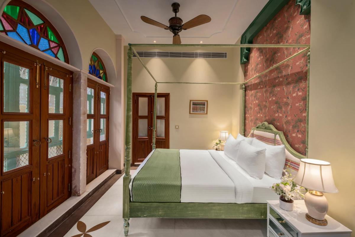 a bedroom with a bed and a stained glass window at Haveli Dharampura & Golden Haveli- UNESCO awarded Boutique Heritage Hotel in New Delhi a bedroom with a bed and a stained glass window at Haveli Dharampura & Golden Haveli- UNESCO awarded Boutique Heritage Hotel in New Delhi