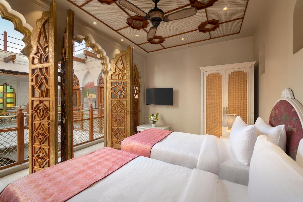 a bedroom with two beds and a balcony at Haveli Dharampura & Golden Haveli- UNESCO awarded Boutique Heritage Hotel in New Delhi a bedroom with two beds and a balcony at Haveli Dharampura & Golden Haveli- UNESCO awarded Boutique Heritage Hotel in New Delhi