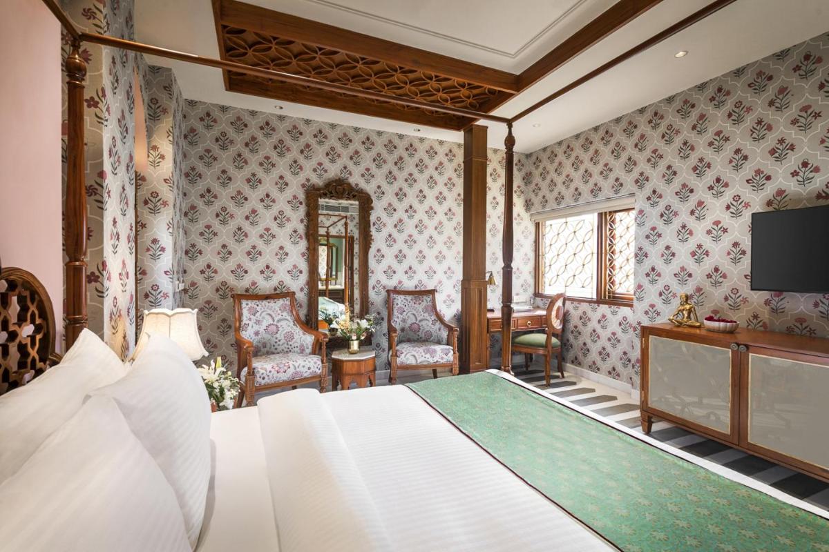 a bedroom with a bed and a television and chairs at Haveli Dharampura & Golden Haveli- UNESCO awarded Boutique Heritage Hotel in New Delhi a bedroom with a bed and a television and chairs at Haveli Dharampura & Golden Haveli- UNESCO awarded Boutique Heritage Hotel in New Delhi