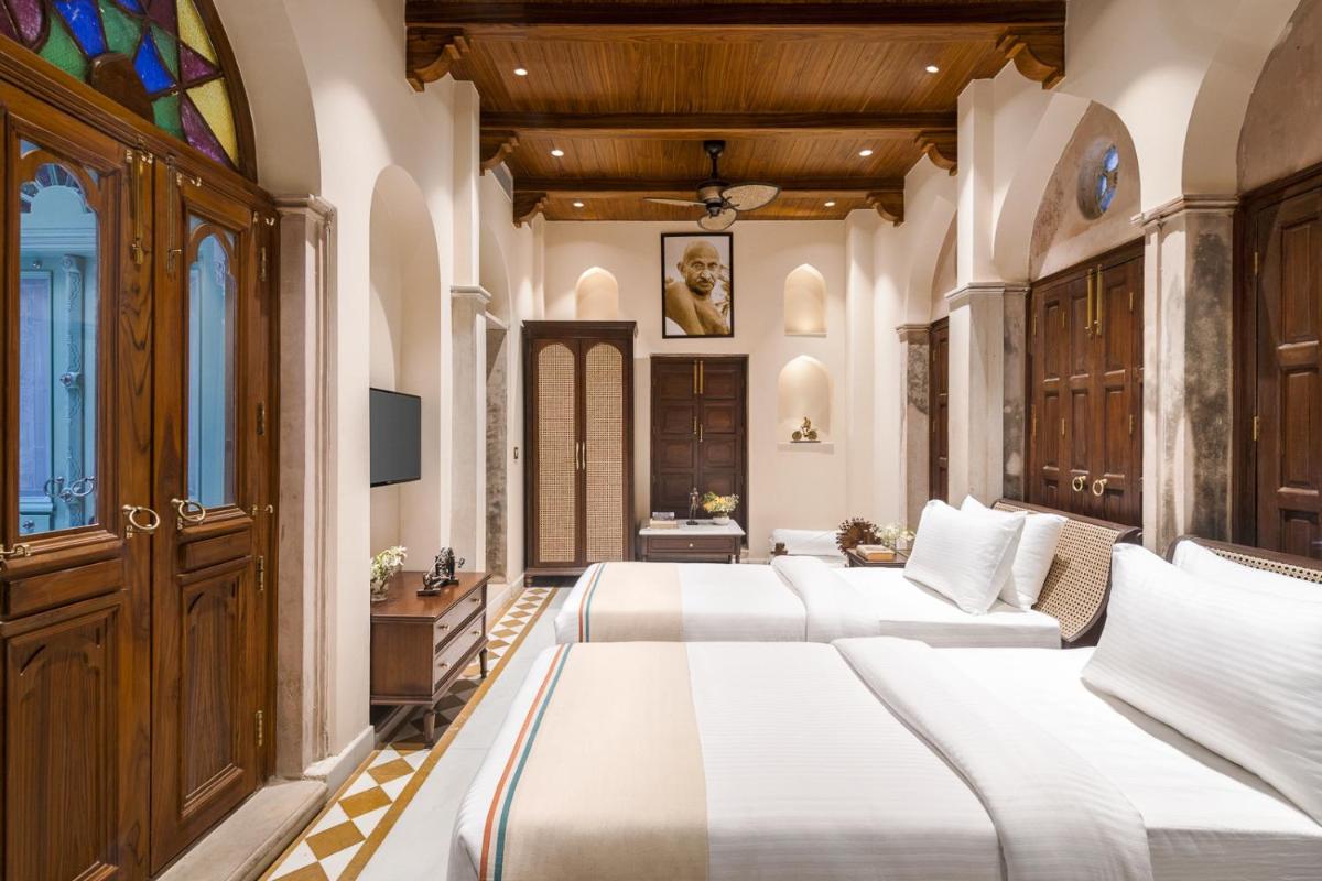 a bedroom with four beds in a room with a window at Haveli Dharampura & Golden Haveli- UNESCO awarded Boutique Heritage Hotel in New Delhi a bedroom with four beds in a room with a window at Haveli Dharampura & Golden Haveli- UNESCO awarded Boutique Heritage Hotel in New Delhi