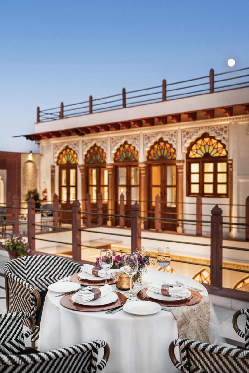 a table with plates and wine glasses on a patio at Haveli Dharampura & Golden Haveli- UNESCO awarded Boutique Heritage Hotel in New Delhi a table with plates and wine glasses on a patio at Haveli Dharampura & Golden Haveli- UNESCO awarded Boutique Heritage Hotel in New Delhi