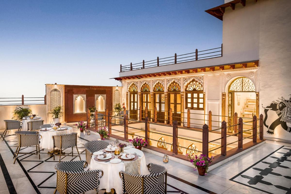 a restaurant with tables and chairs on a patio at Haveli Dharampura & Golden Haveli- UNESCO awarded Boutique Heritage Hotel in New Delhi a restaurant with tables and chairs on a patio at Haveli Dharampura & Golden Haveli- UNESCO awarded Boutique Heritage Hotel in New Delhi