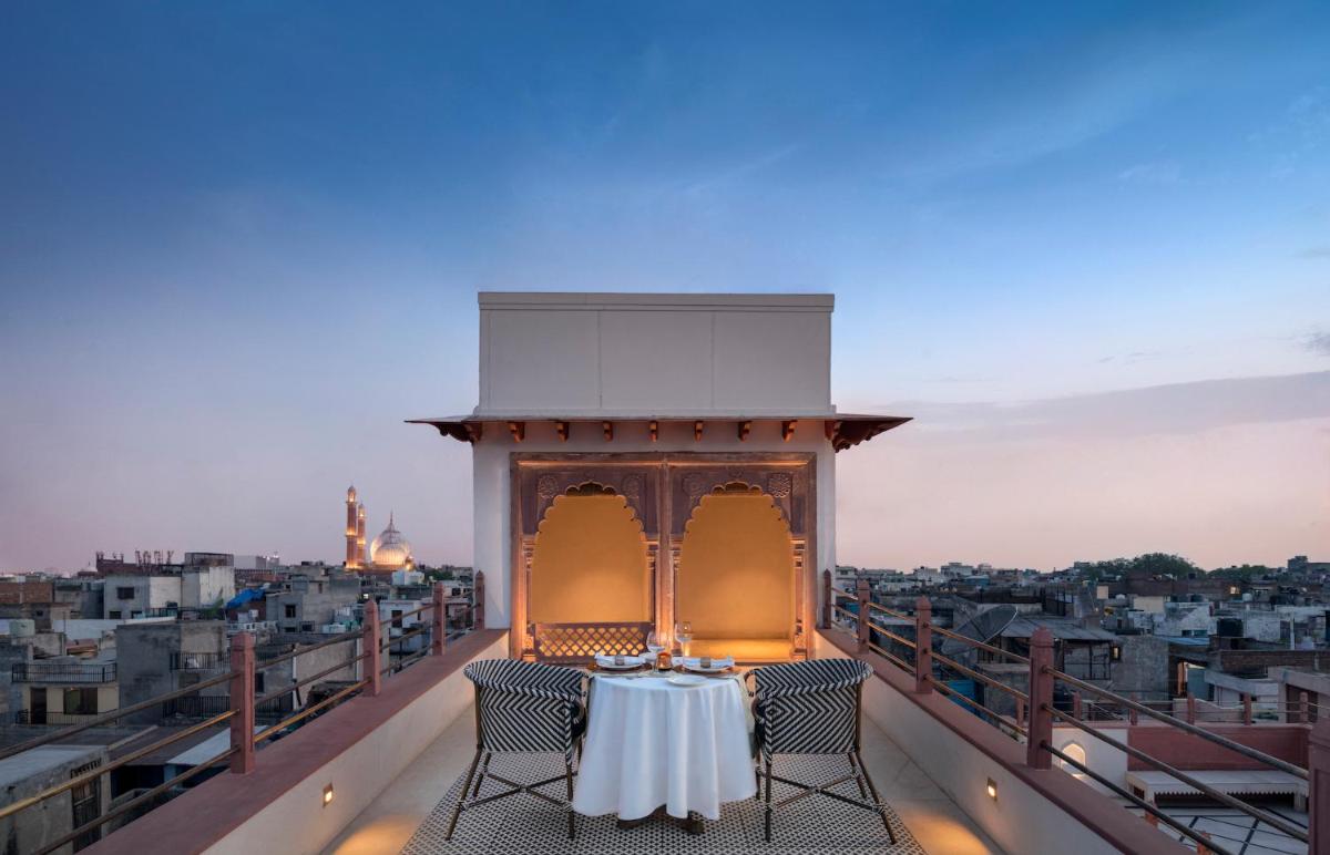 a table on a balcony with a view of a city at Haveli Dharampura & Golden Haveli- UNESCO awarded Boutique Heritage Hotel in New Delhi a table on a balcony with a view of a city at Haveli Dharampura & Golden Haveli- UNESCO awarded Boutique Heritage Hotel in New Delhi