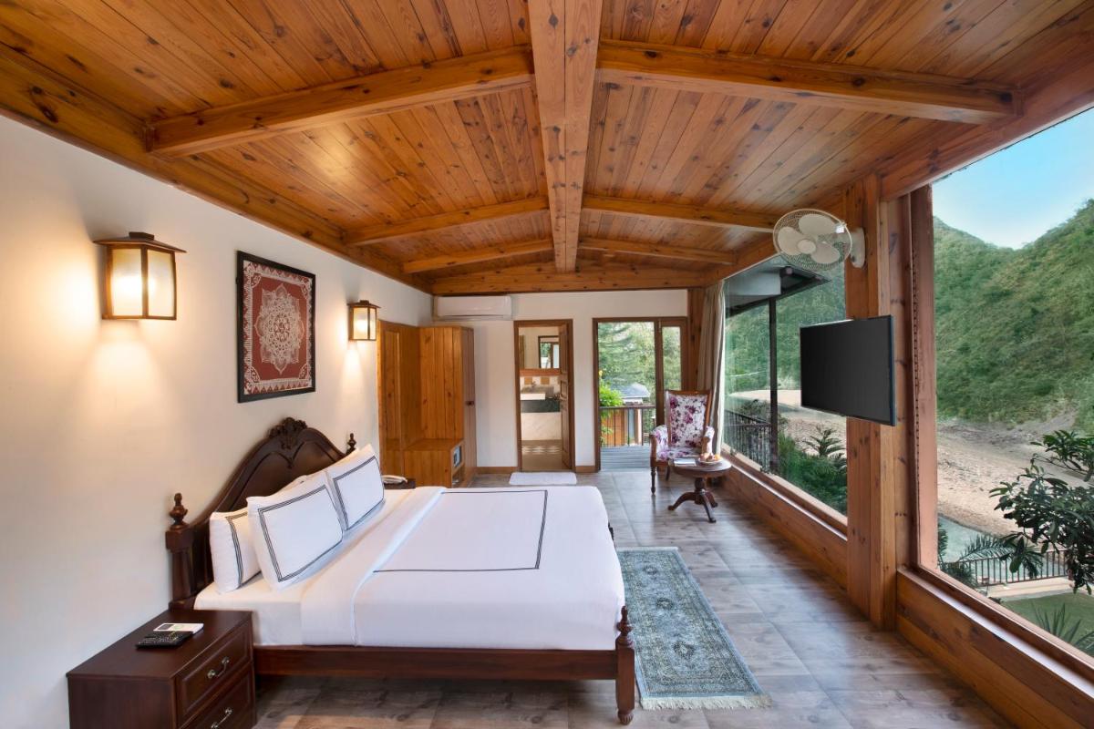 a bedroom with a bed and a large window at Raga on the Ganges, Rishikesh in Rishīkesh