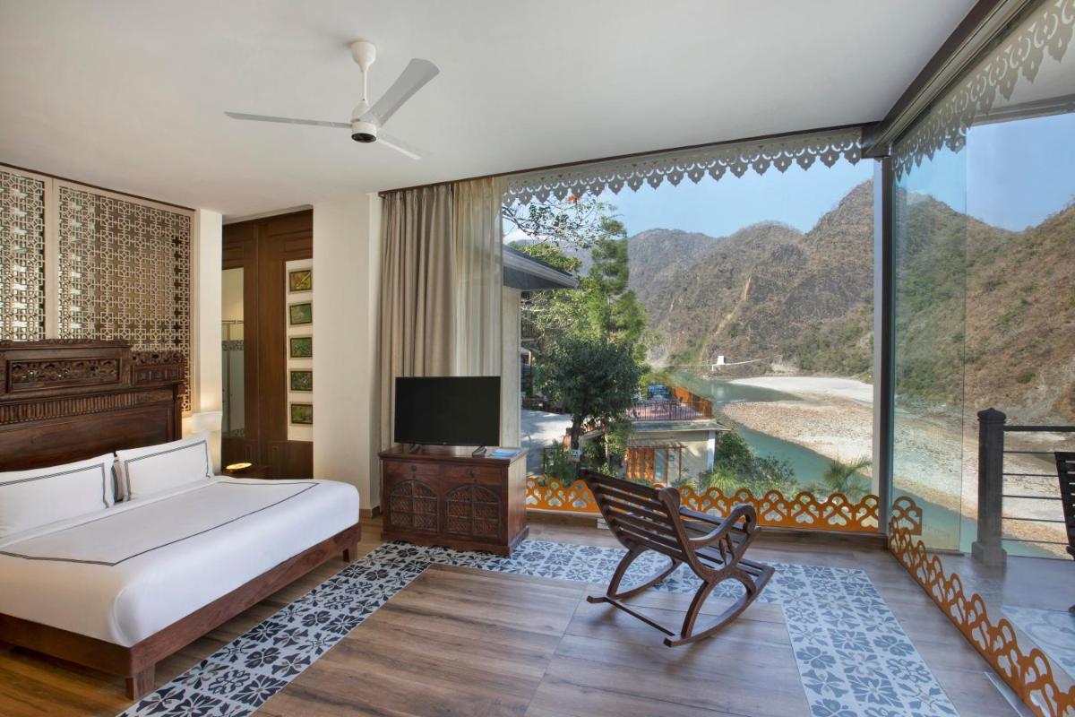 a bedroom with a bed and a large window at Raga on the Ganges, Rishikesh in Rishīkesh