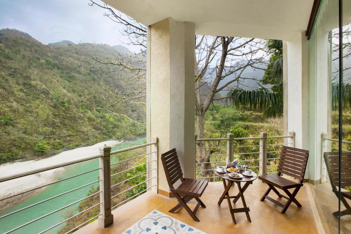 a balcony with two chairs and a table with a view at Raga on the Ganges, Rishikesh in Rishīkesh