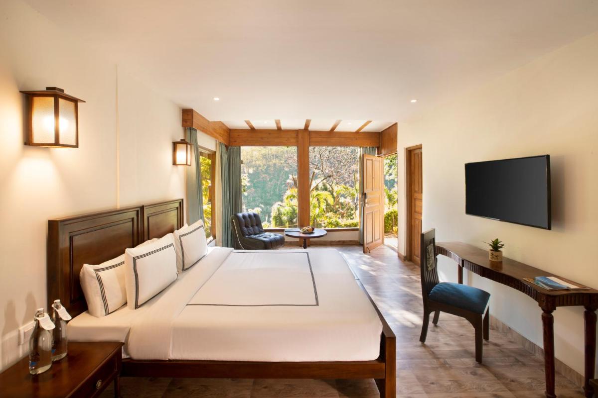 a bedroom with a large bed with a desk and a television at Raga on the Ganges, Rishikesh in Rishīkesh +41 photos