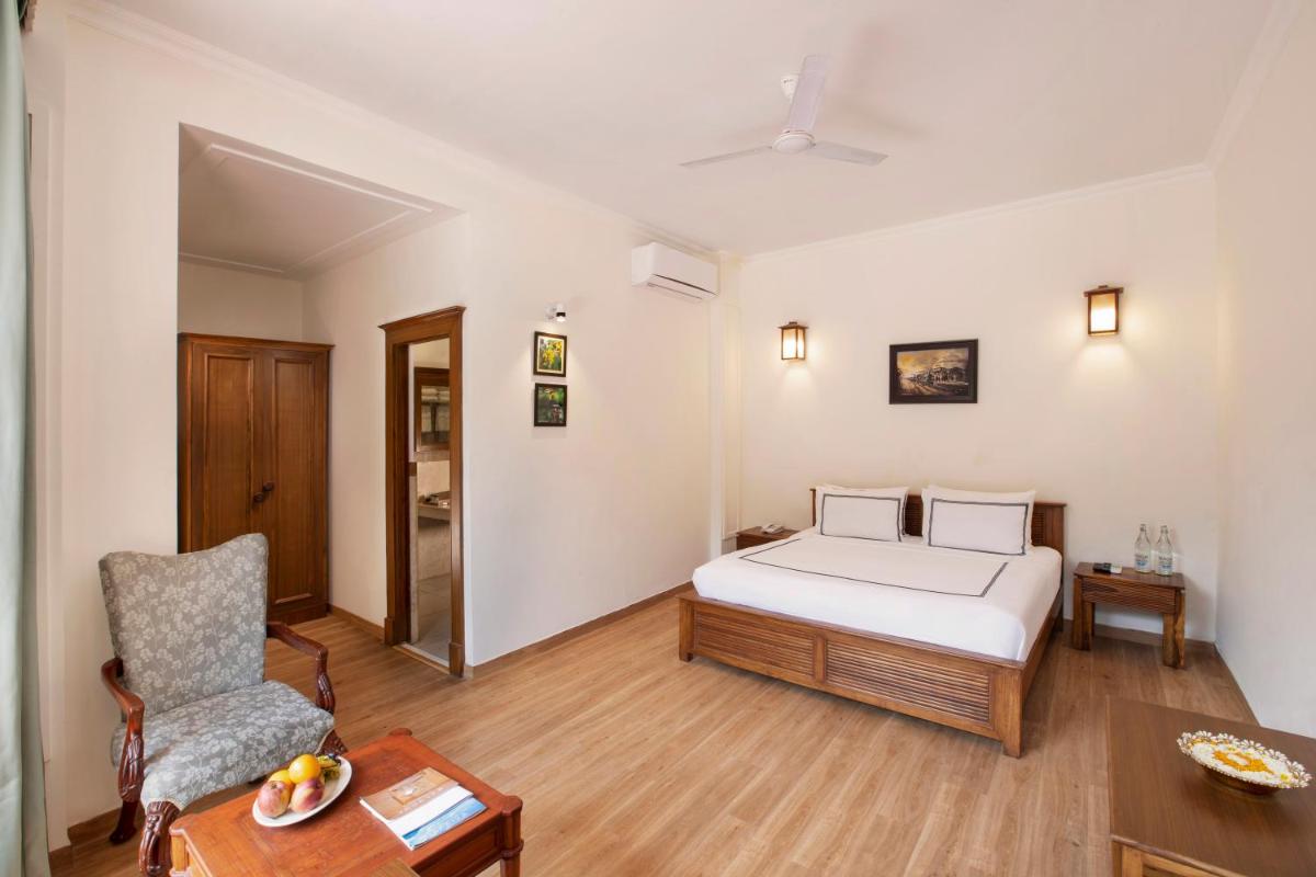 a bedroom with a bed and a chair and a table at Raga on the Ganges, Rishikesh in Rishīkesh