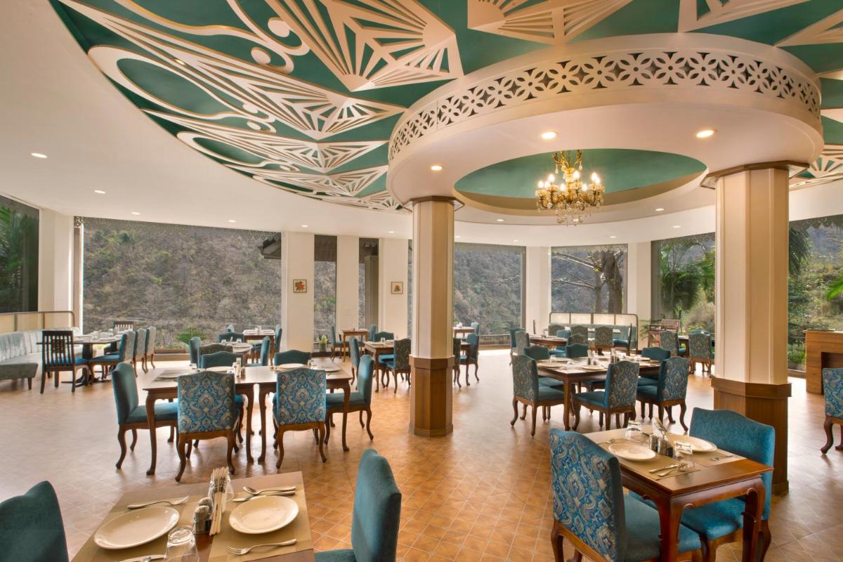 a dining room with tables and chairs and a ceiling at Raga on the Ganges, Rishikesh in Rishīkesh