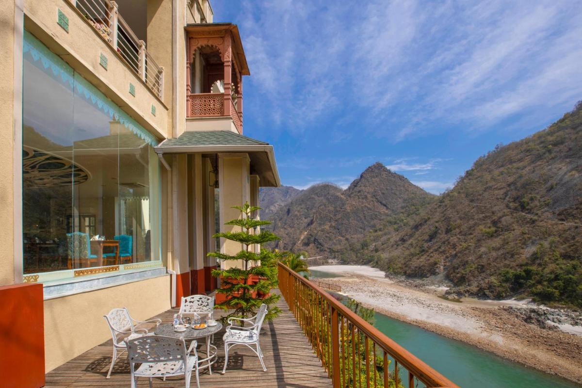 a balcony with a table and chairs overlooking a river at Raga on the Ganges, Rishikesh in Rishīkesh