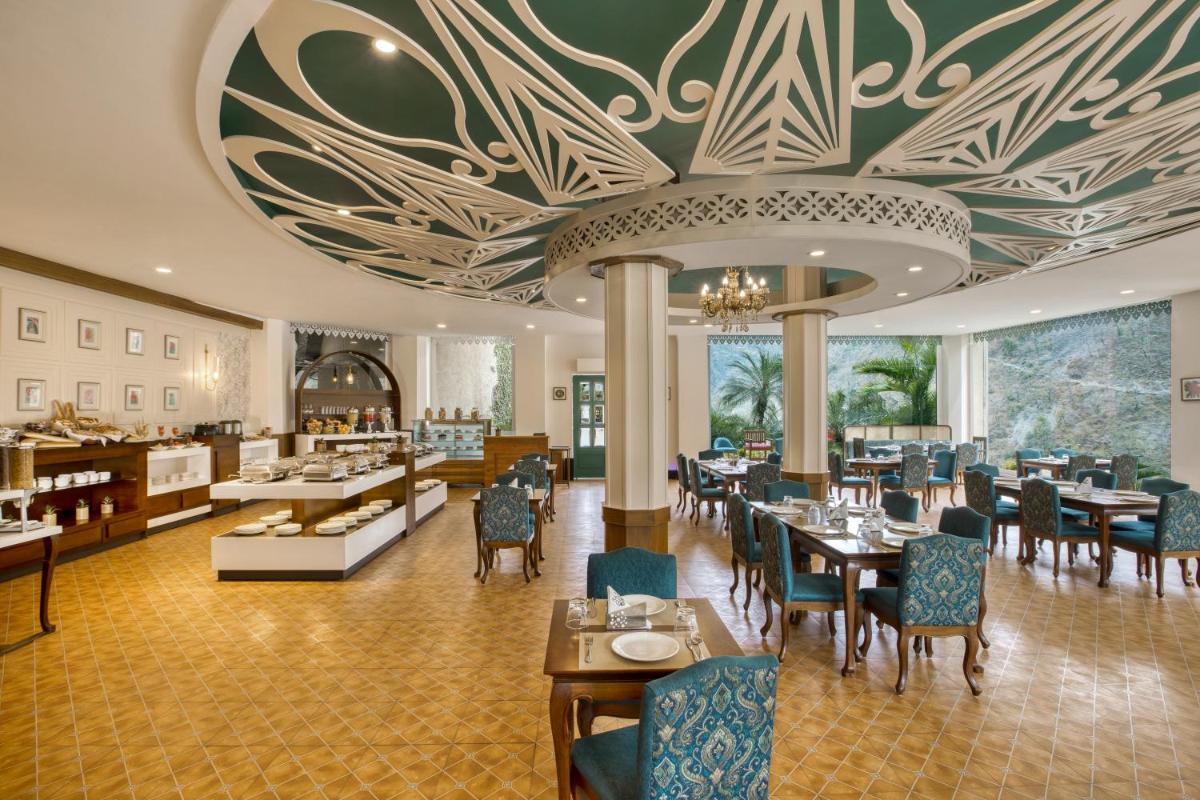 a restaurant with tables and chairs and a ceiling at Raga on the Ganges, Rishikesh in Rishīkesh