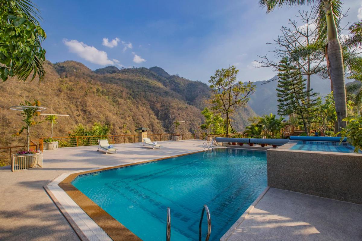a swimming pool with mountains in the background at Raga on the Ganges, Rishikesh in Rishīkesh