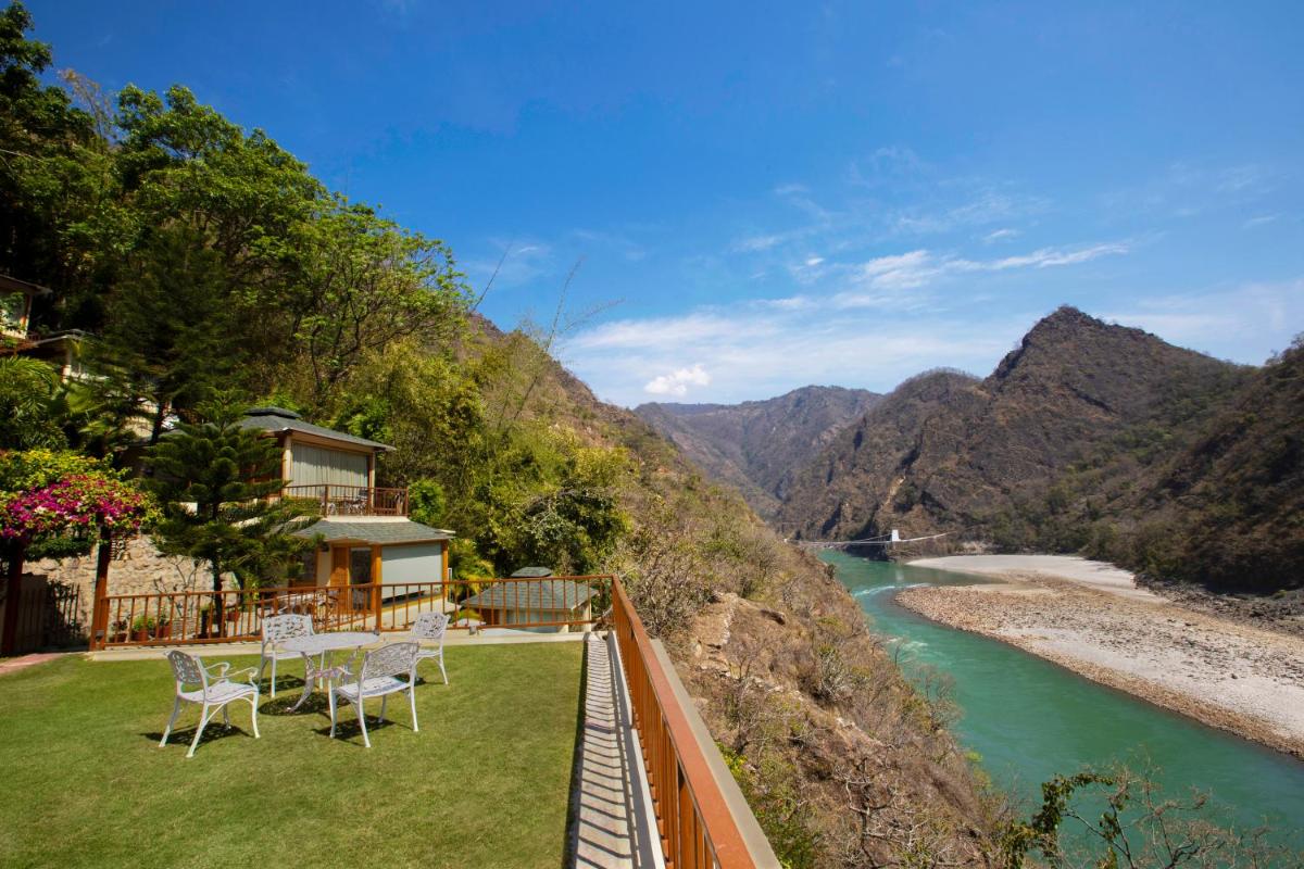 a balcony with tables and chairs next to a river at Raga on the Ganges, Rishikesh in Rishīkesh