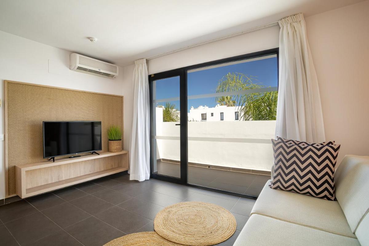 Una sala de estar con un televisor de pantalla plana y un sofá. en Migjorn Ibiza Suites & Spa, en Playa d'en Bossa
