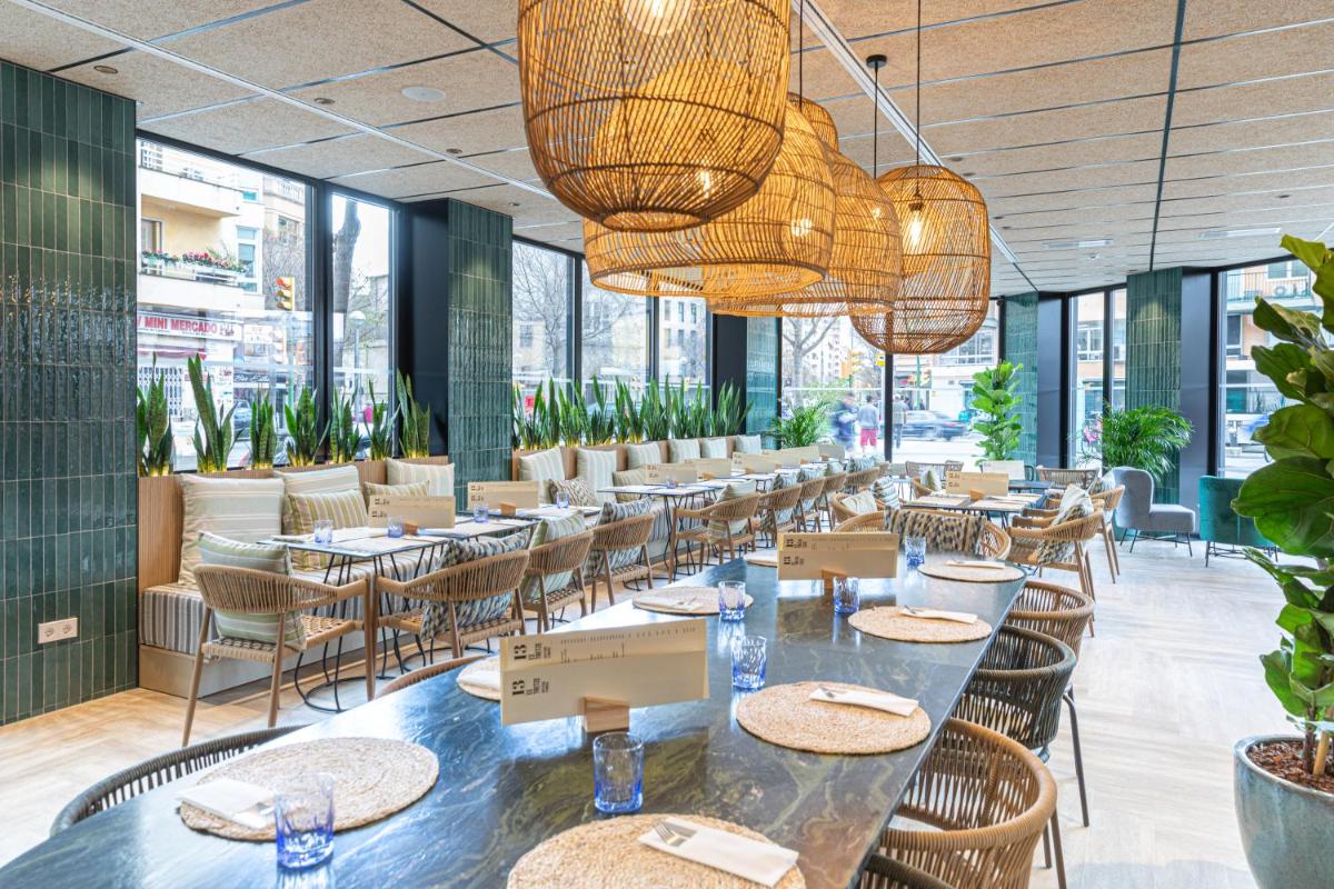 Un restaurante con mesas y sillas y grandes ventanales. en JS Palma Plaza, en Palma de Mallorca