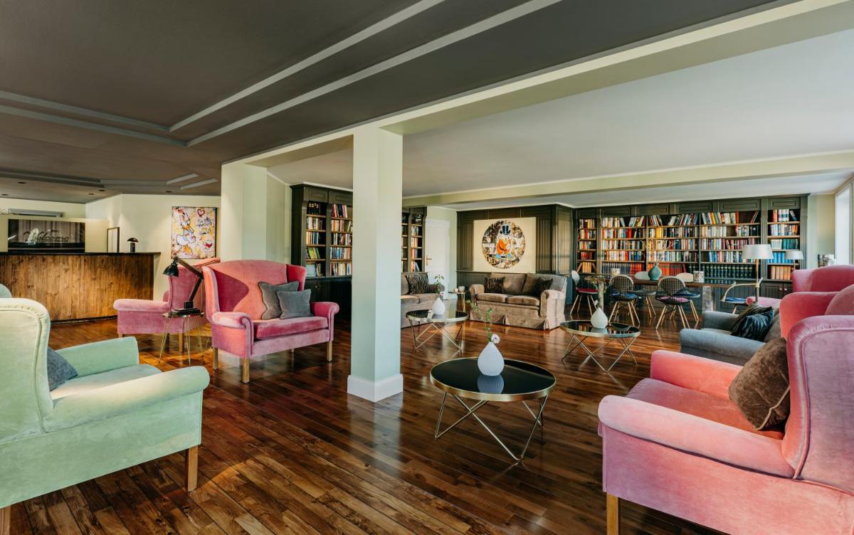 ein großes Wohnzimmer mit rosa Stühlen und Büchern in der Unterkunft Relais & Châteaux Landhaus Stricker in Tinnum