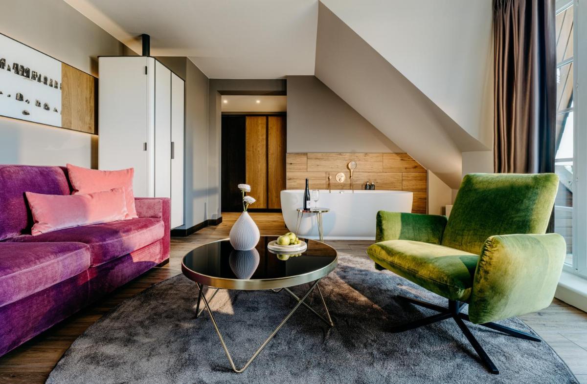 ein Wohnzimmer mit lila und grünen Stühlen und einem Tisch in der Unterkunft Relais & Châteaux Landhaus Stricker in Tinnum ein Wohnzimmer mit lila und grünen Stühlen und einem Tisch in der Unterkunft Relais & Châteaux Landhaus Stricker in Tinnum