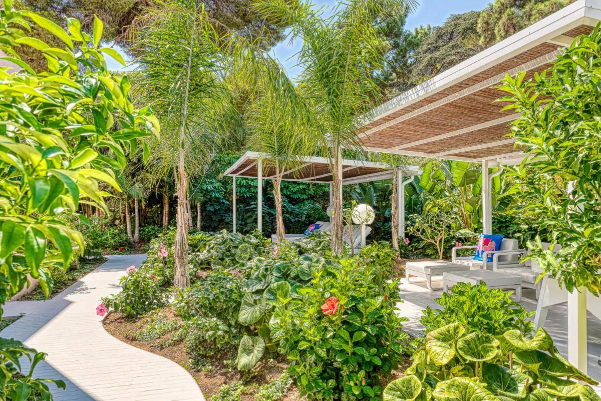 un jardín con un dosel de madera y plantas en The Pink Elephant Hotel, en S'Agaró