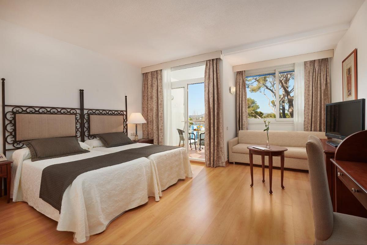 Un dormitorio con una cama grande y una sala de estar. en Hipotels Eurotel Punta Rotja Spa-Golf, en Costa des Pins
