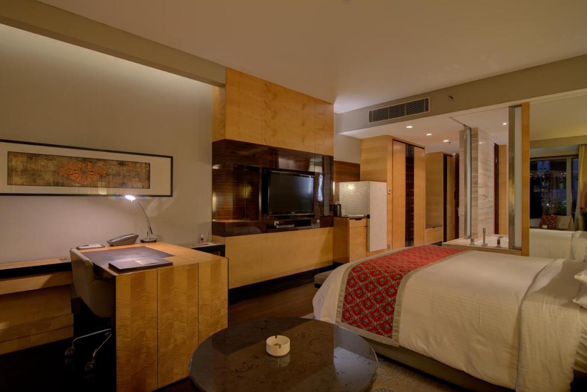 a hotel room with a bed and a flat screen tv at JW Marriott Hotel New Delhi Aerocity in New Delhi a hotel room with a bed and a flat screen tv at JW Marriott Hotel New Delhi Aerocity in New Delhi