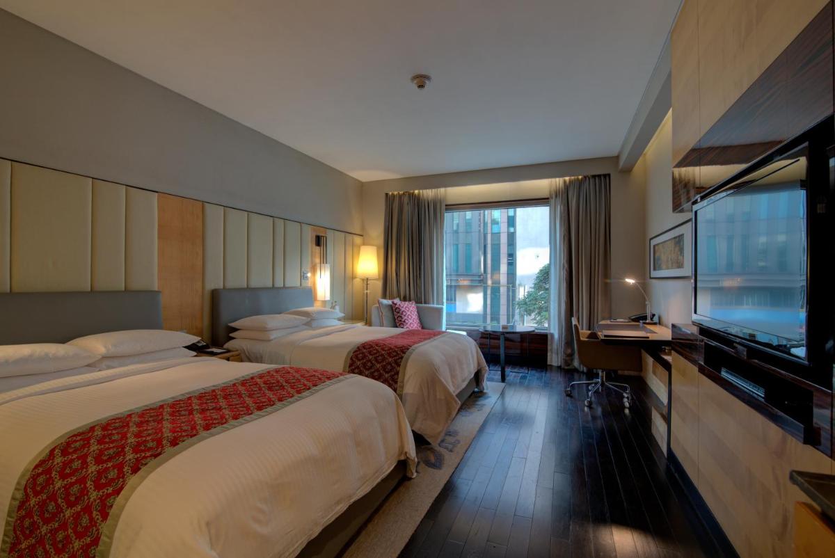 a hotel room with two beds and a flat screen tv at JW Marriott Hotel New Delhi Aerocity in New Delhi a hotel room with two beds and a flat screen tv at JW Marriott Hotel New Delhi Aerocity in New Delhi