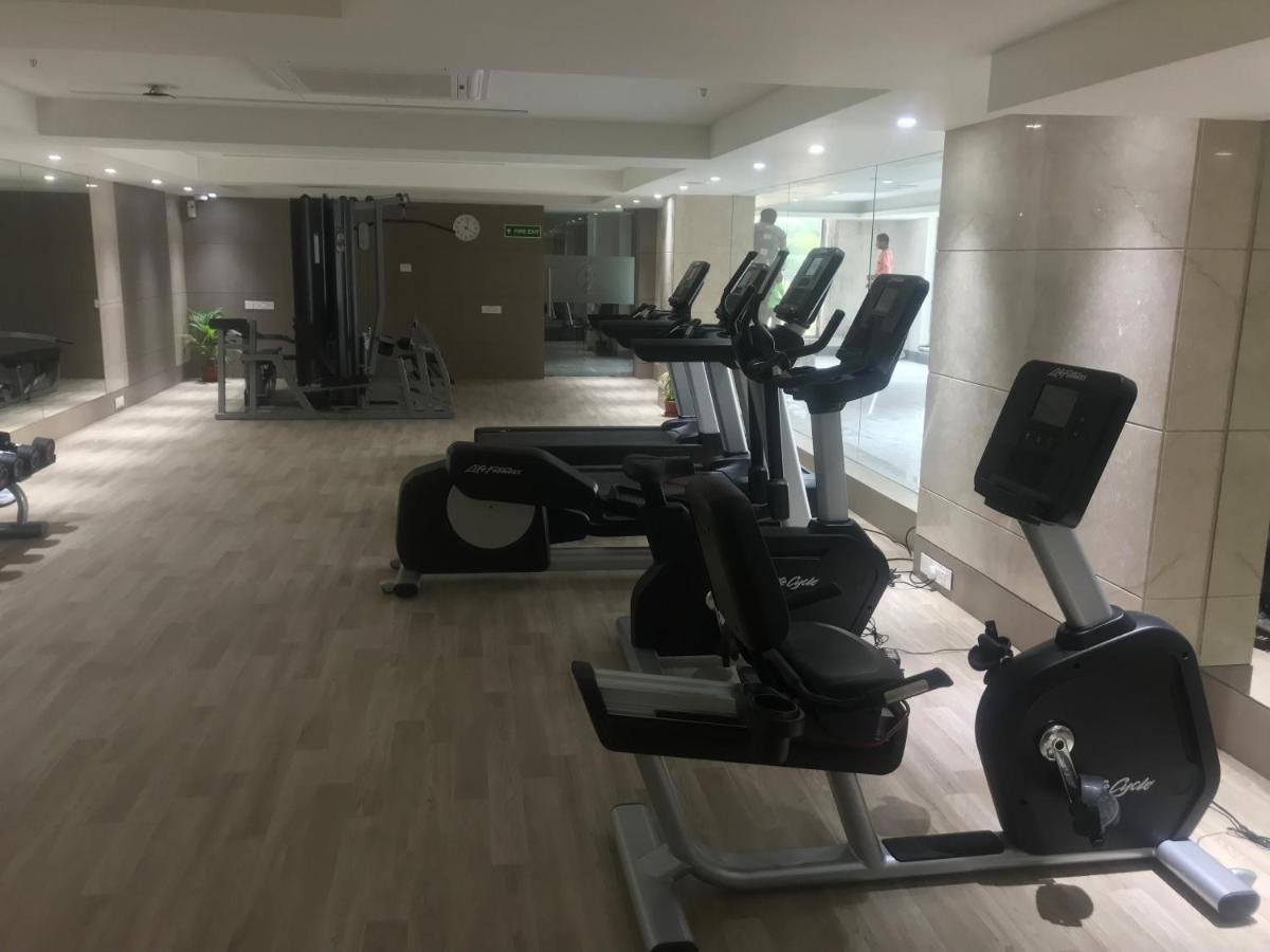 a gym with a row of treadmills and mirrors at Ramada Plaza by Wyndham Lucknow in Lucknow