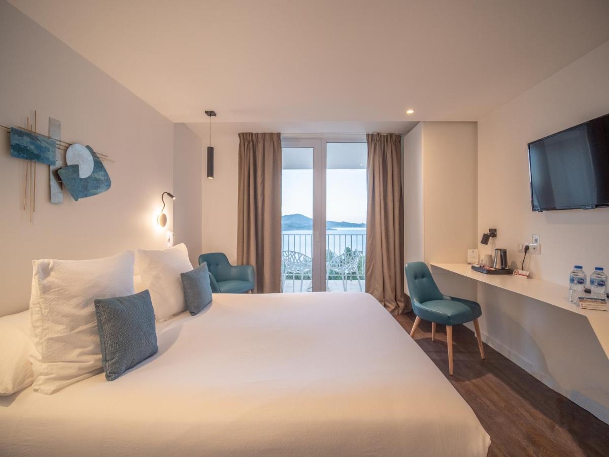 une chambre d'hôtel avec un grand lit blanc et un bureau dans l'établissement Côté Thalasso Hôtel & Spa Marin, à Banyuls-sur-Mer