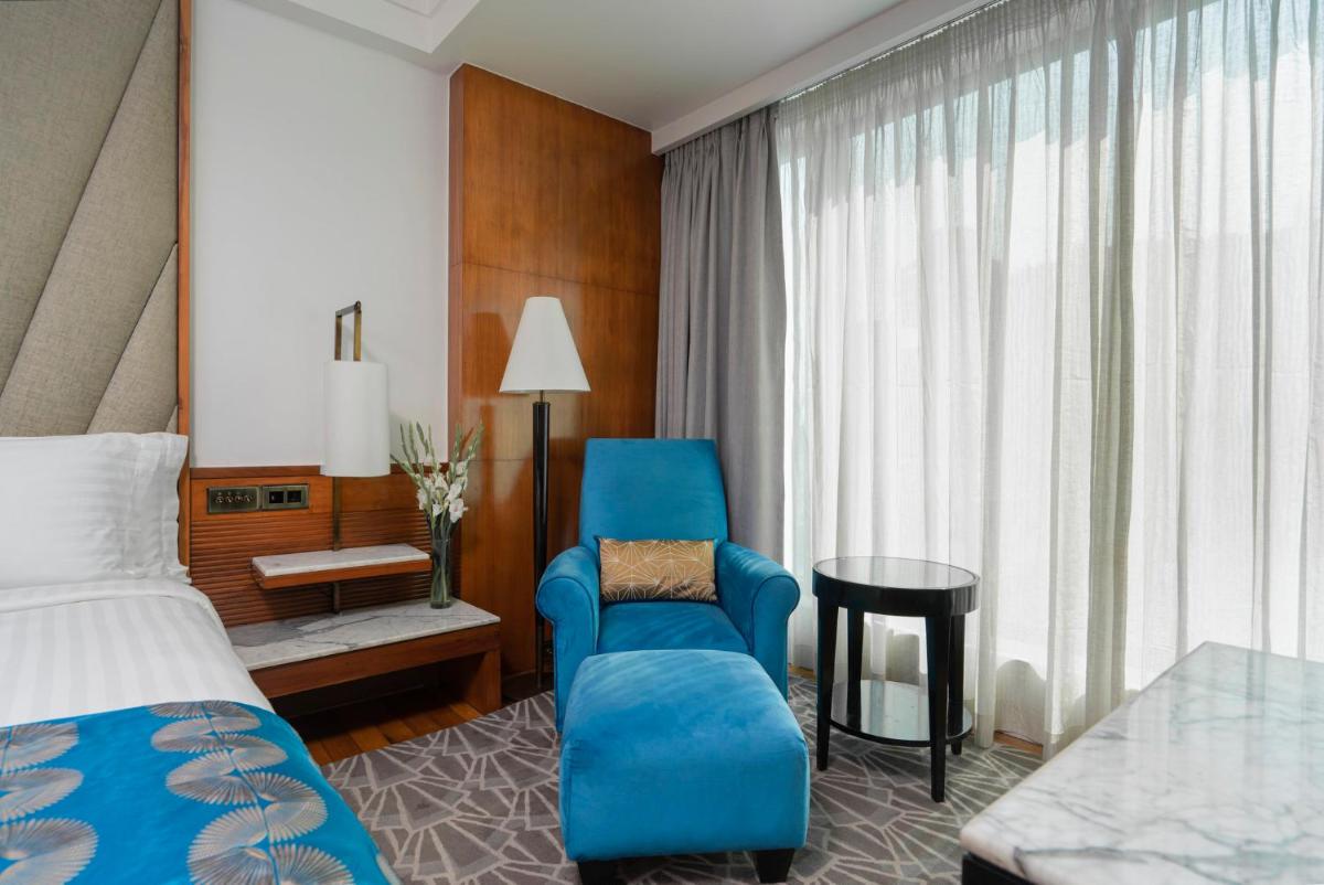 a hotel room with a bed and a blue chair at InterContinental Marine Drive Mumbai by IHG in Mumbai
