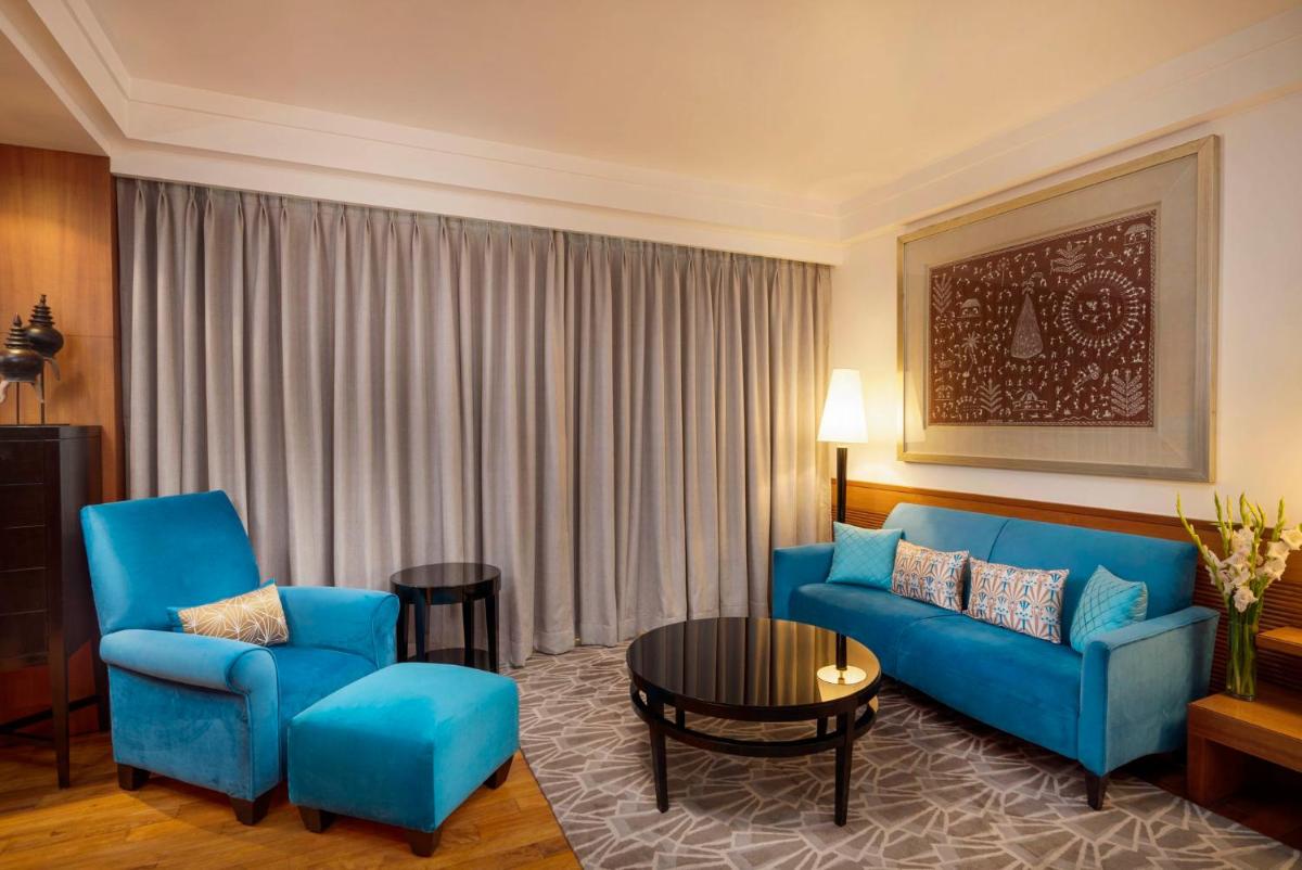a living room with a blue couch and two chairs at InterContinental Marine Drive Mumbai by IHG in Mumbai