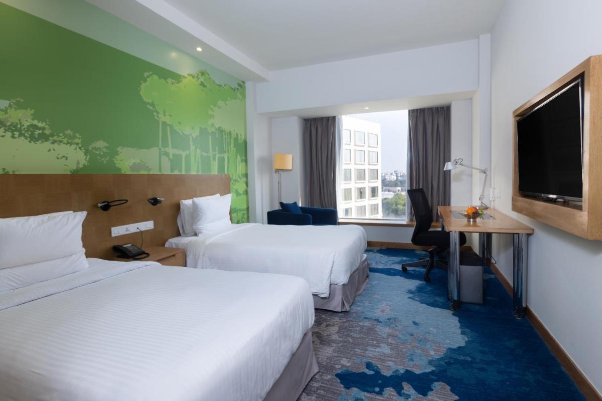 a hotel room with two beds and a flat screen tv at Novotel Hyderabad Convention Centre in Hyderabad a hotel room with two beds and a flat screen tv at Novotel Hyderabad Convention Centre in Hyderabad