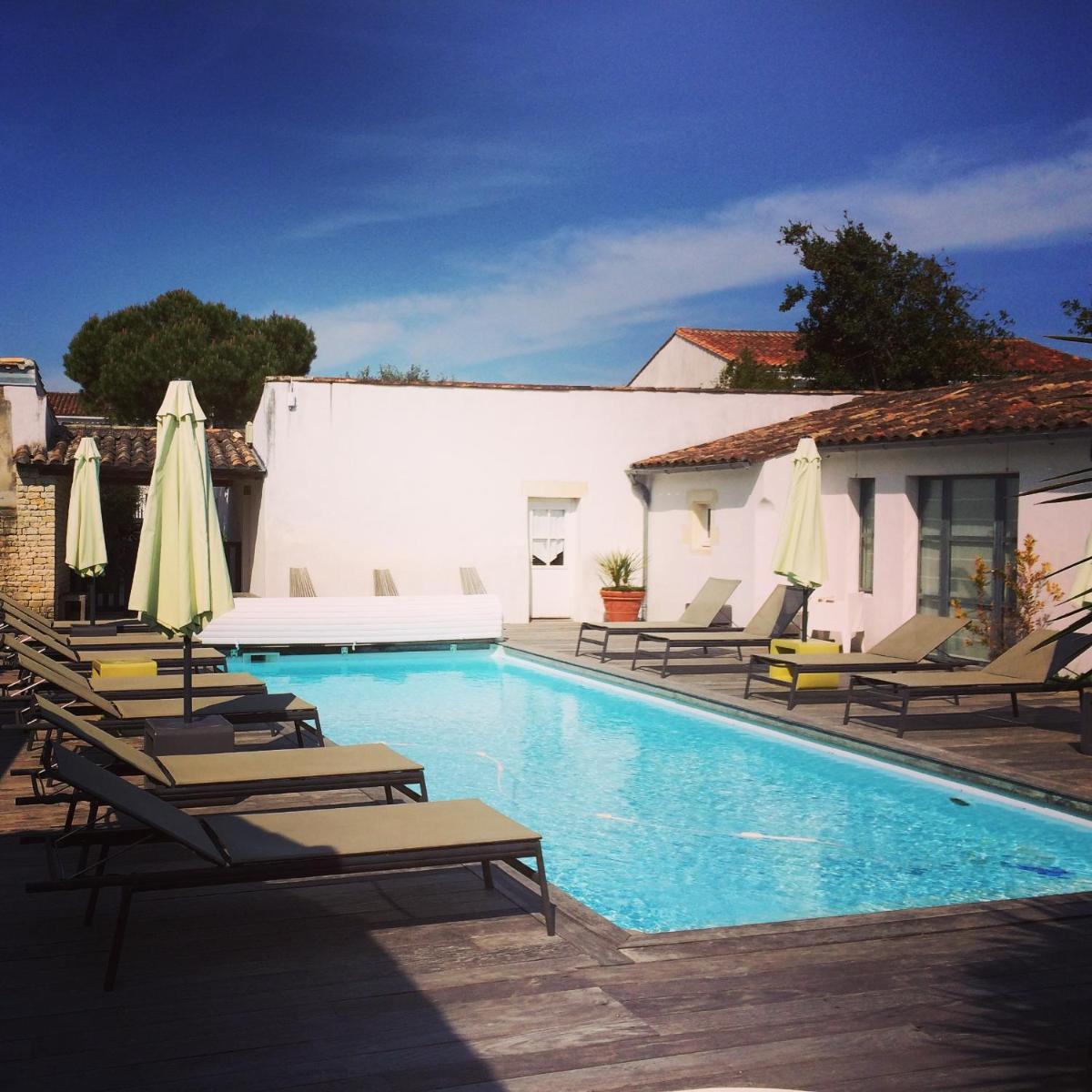une piscine avec chaises longues et parasols dans l'établissement Hotel L'Océan, au Bois-Plage-en-Ré 44 autres photos