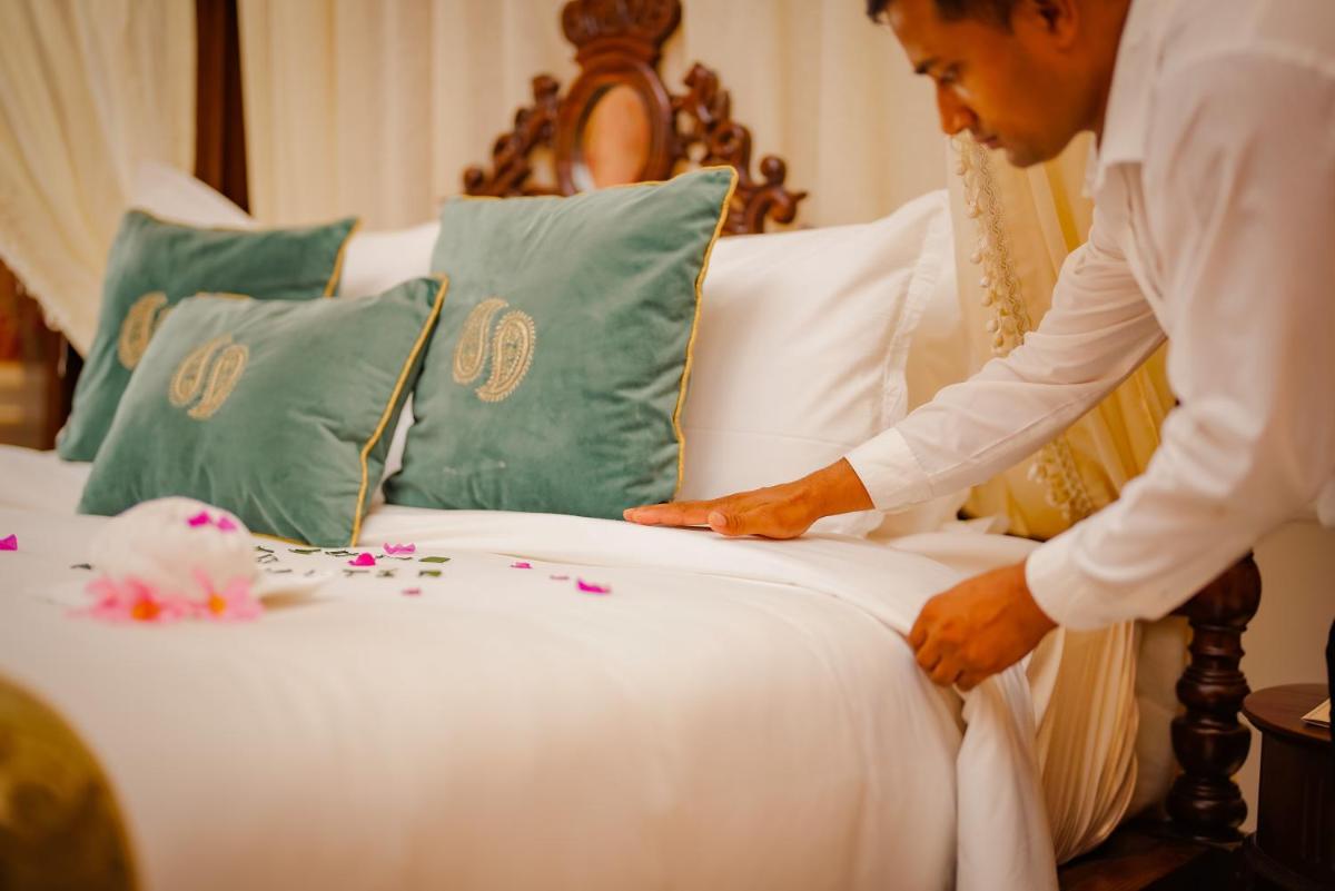 a man making a bed with flowers on it at Raajkutir - IHCL SeleQtions in Kolkata