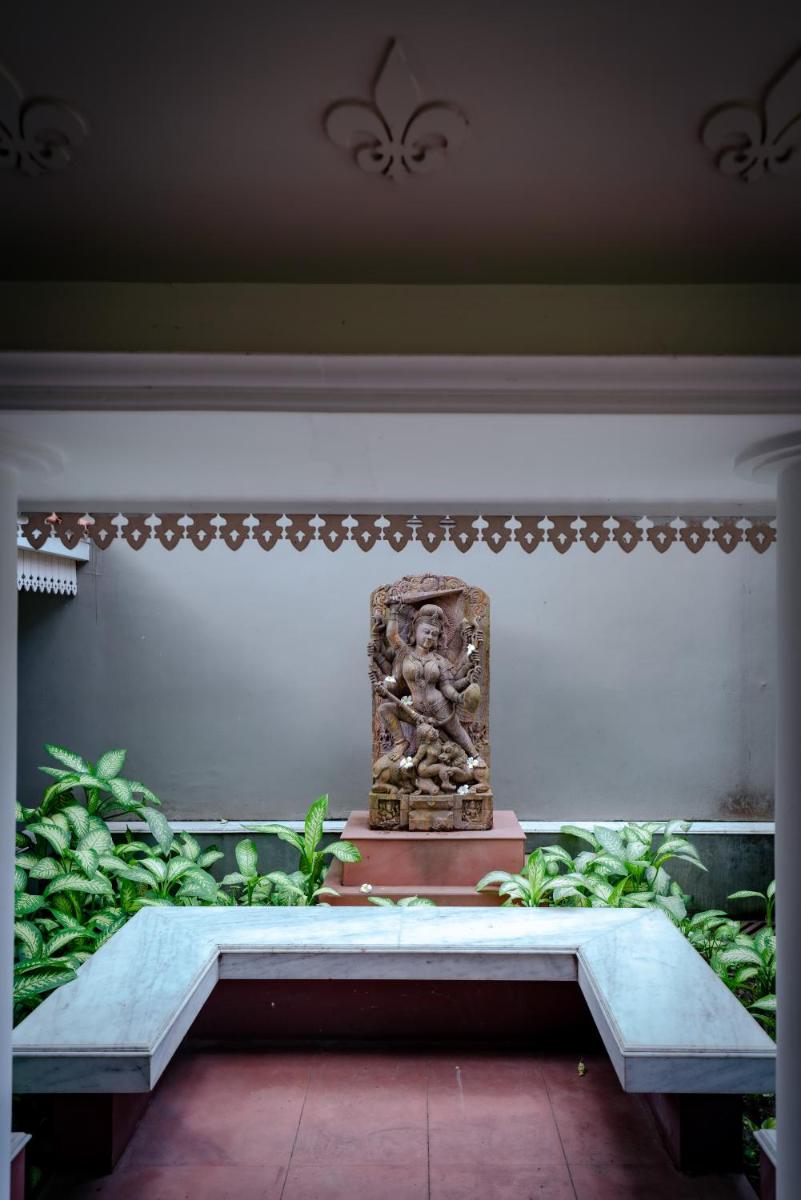 a statue sitting on a bench in a room with plants at Raajkutir - IHCL SeleQtions in Kolkata