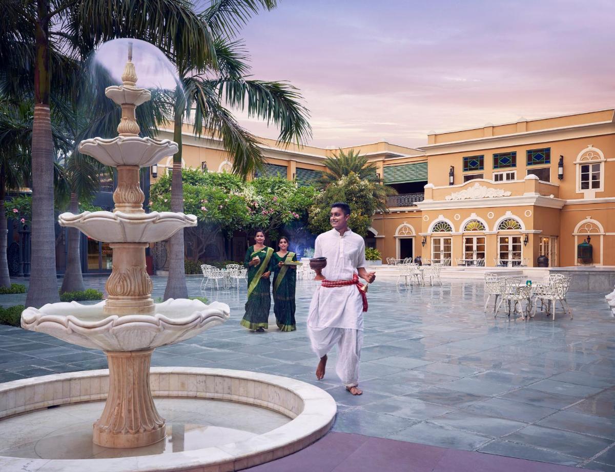 a man walking in front of a fountain in a courtyard at Raajkutir - IHCL SeleQtions in Kolkata