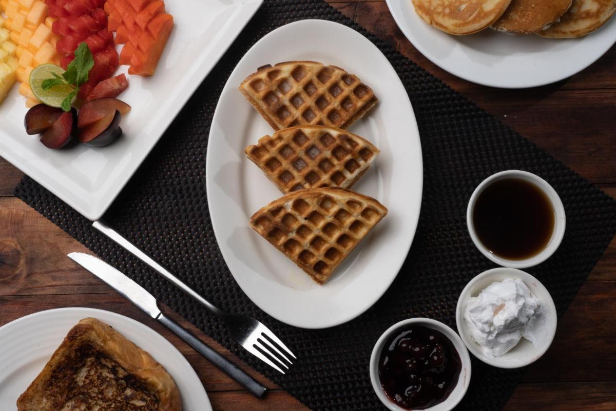a table topped with plates of waffles and fruit at Bengaluru Marriott Hotel Whitefield in Bengaluru +90 photos