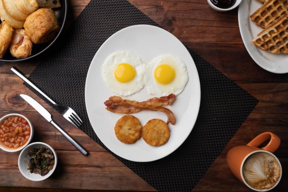 a white plate with eggs and bacon on a table at Bengaluru Marriott Hotel Whitefield in Bengaluru