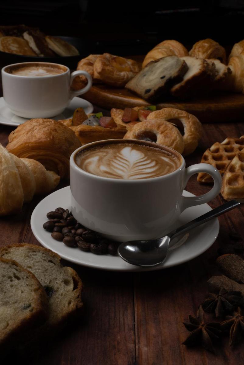 a cup of coffee sitting on a plate with bread at Bengaluru Marriott Hotel Whitefield in Bengaluru