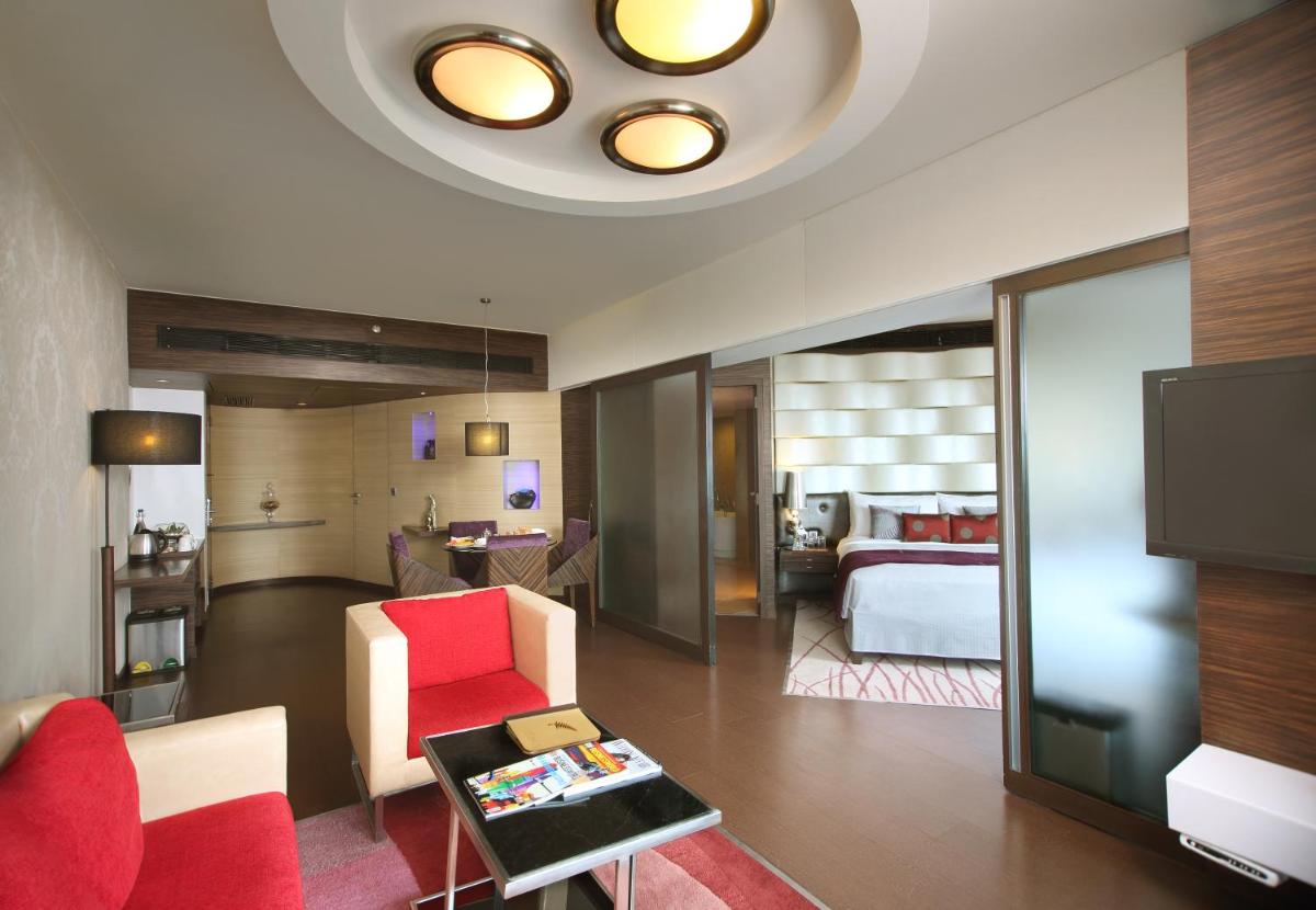 a living room with a red chair and a bedroom at Fortune Select SG Highway, Ahmedabad - Member ITC Hotels' Group in Ahmedabad